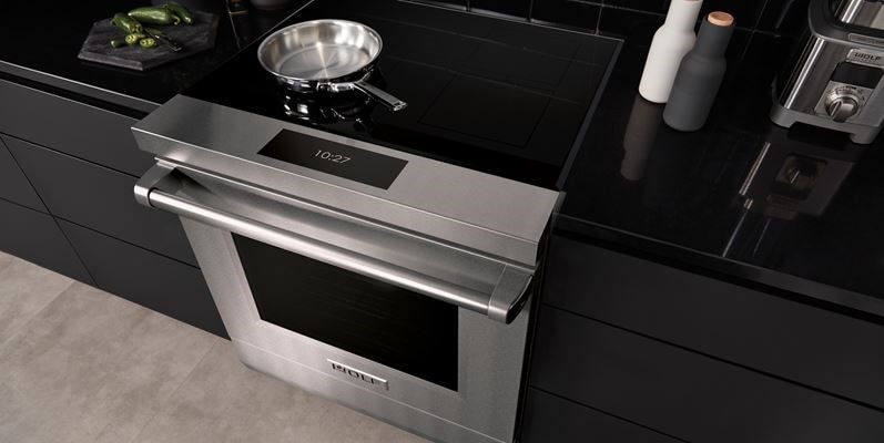 Wolf 36-inch Contemporary Induction Cooktop (CI36560T) featuring sleek black glass surface installed flush in a modern Mediterranean kitchen design.