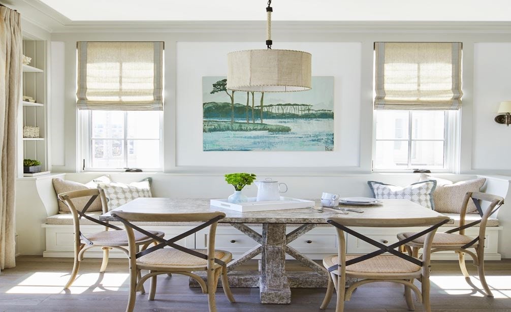 The adjacent dining area, with a cozy bench and chairs, provides space for larger gatherings in Beachfront Escape by Catherine Zanghi.
