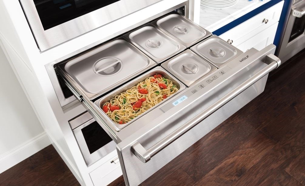 The Wolf 30&quot; Warming Drawer (WD30) displaying it's capacity for holding several dishes while looking great with dark wood floors