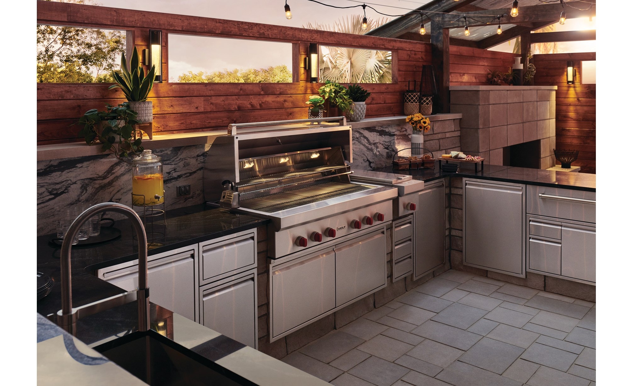 The Wolf 54" Outdoor Gas Grill (OG54) shown blending seamlessly into a rich modern outdoor kitchen design offering pro quality amenities.