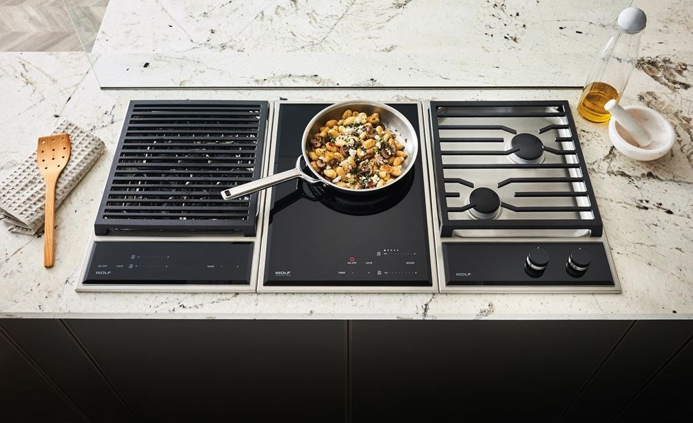 The Wolf 15&quot; Transitional Induction Cooktop (CI152TF/S) shown set flush in artistic black and white speckled granite countertop