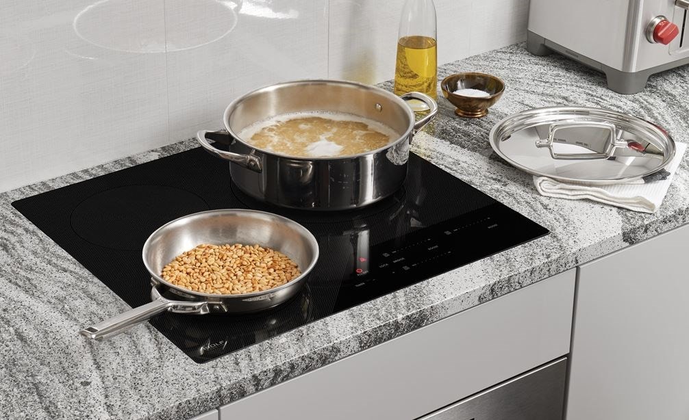 Wolf 24&quot; Contemporary Induction Cooktop (CI243C/B) shown set flush in dark grey black and white swirl granite countertop