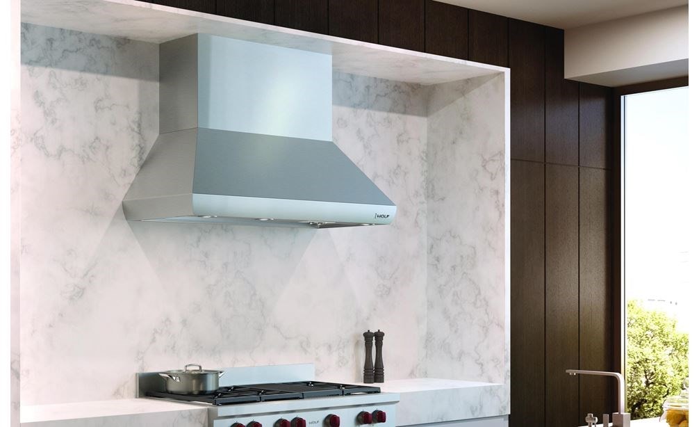The Wolf 54&quot; Pro Wall Chimney Hood (PWC542418) shown here framed expertly in a rich marble backsplash is the crown jewel of any kitchen 
