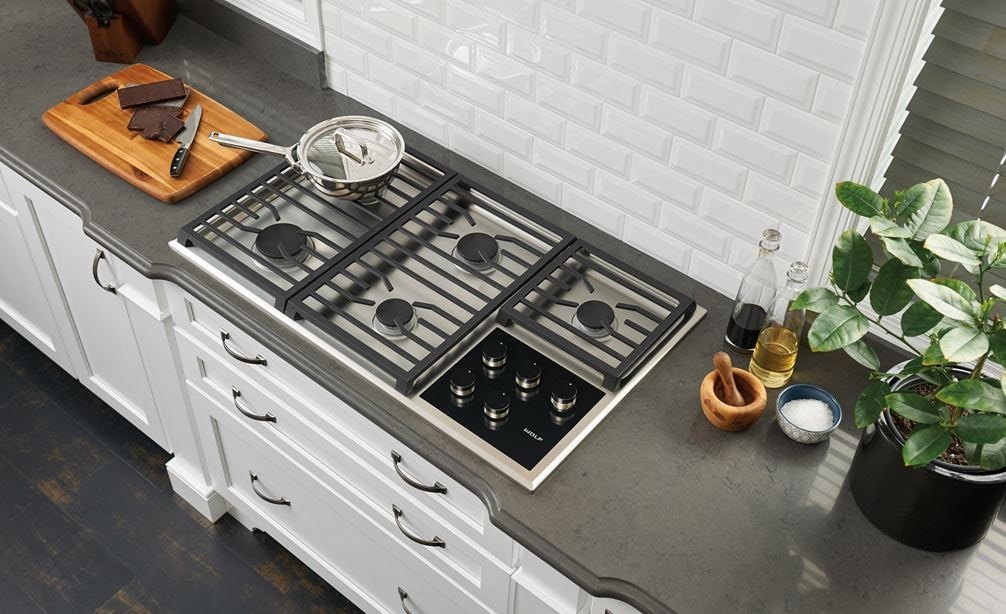 The Wolf 36&quot; Transitional Gas Cooktop 5 Burners (CG365T/S) centered in clean smooth granite countertop for a classic kitchen design