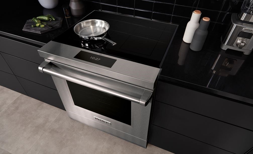 Wolf 30&#34; Professional Induction Range (IR30450/S/P) featured in matte black cabinetry with a stainless steel pan set on its black ceramic glass surface.
