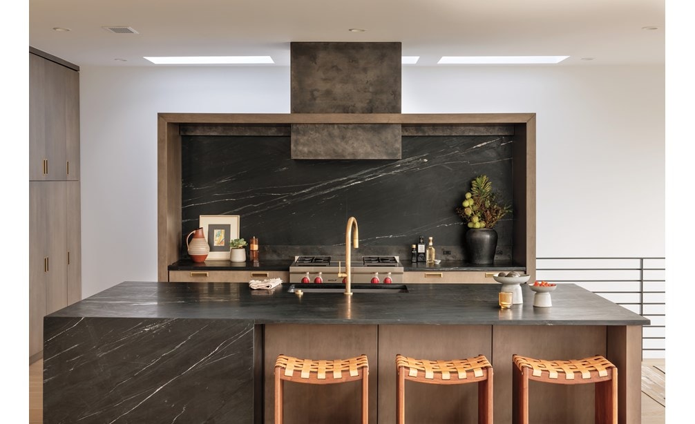 The Wolf 36 Inch Sealed 4 Burner Rangetop and Infrared Griddle installed in a custom wood framed alcove featuring dark marble backsplash with matching kitchen island