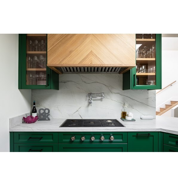 Wolf 36-inch contemporary gas cooktop featured in small space stylish kitchen with green cabinets and marble backsplash.