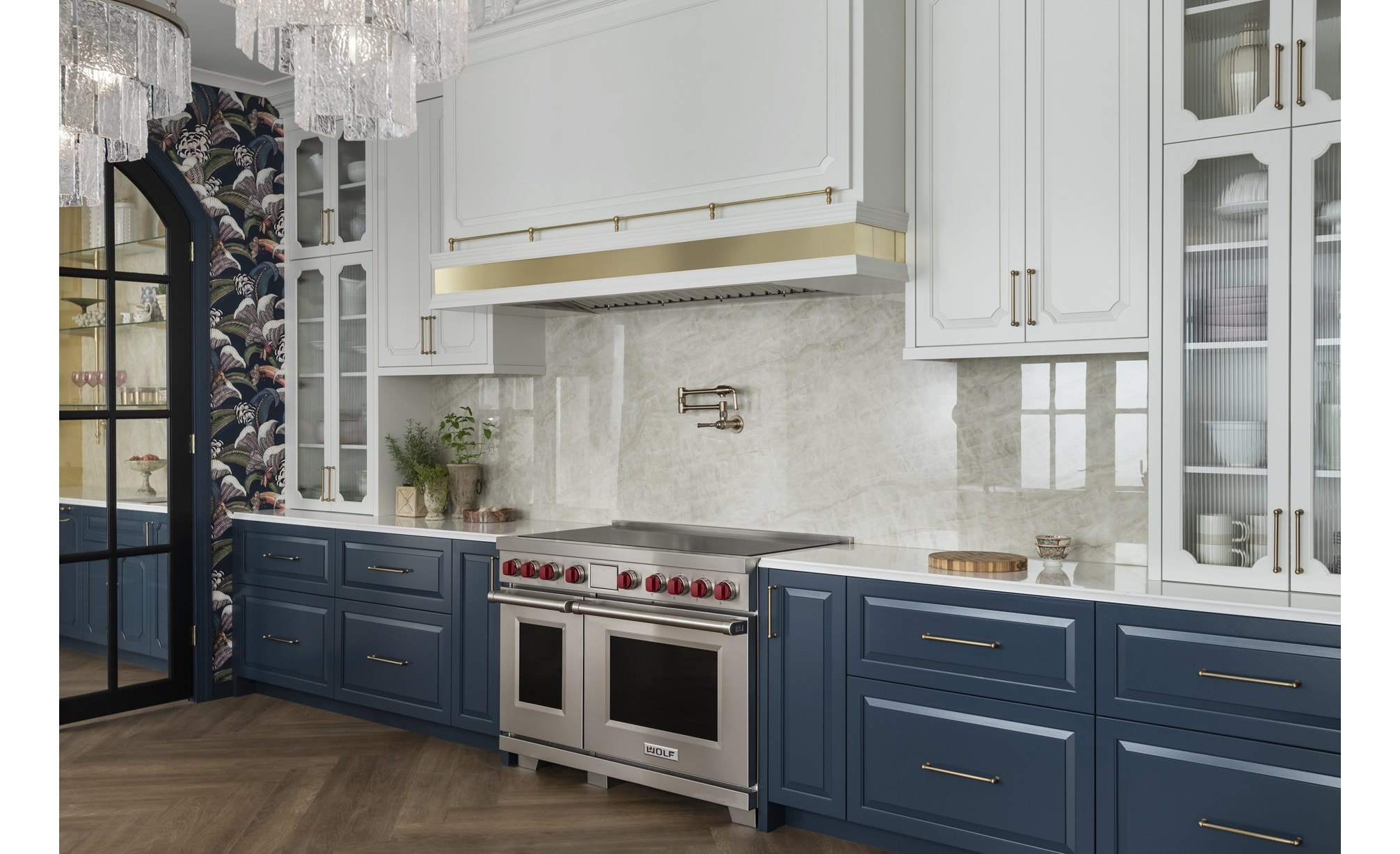 Wolf Professional Induction Range shown in an elegantly appointed modern kitchen featuring tall arched glass upper kitchen cabinets with dark slate blue lower cabinetry.