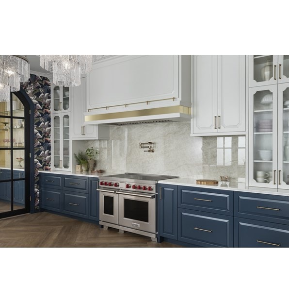 Wolf Professional Induction Range shown in an elegantly appointed modern kitchen featuring tall arched glass upper kitchen cabinets with dark slate blue lower cabinetry.
