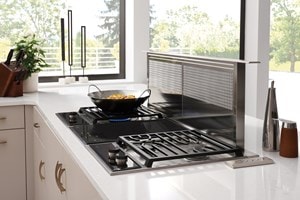The Wolf 15" Transitional Induction Cooktop (CI152TF/S) shown set flush in artistic black and white speckled granite countertop
