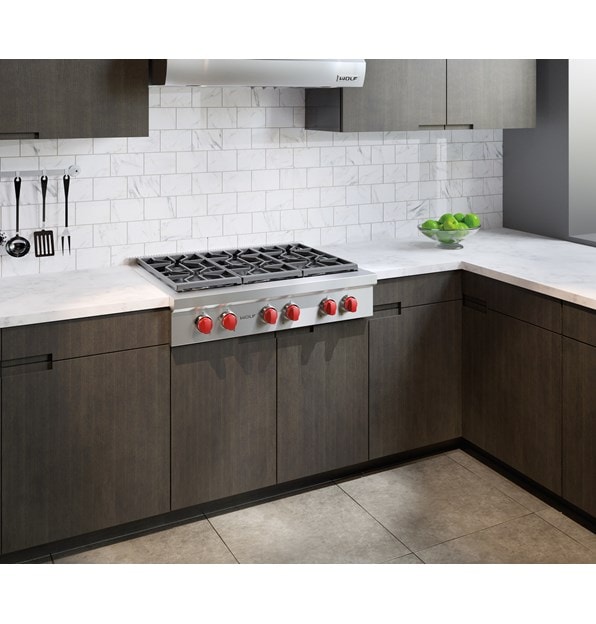 The Wolf 36" Sealed 6 Burner Rangetop (SRT366) shines in this classic kitchen setting next to flat panel cabinets and white brick wall