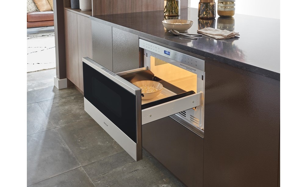 The Wolf 24" Transitional Drawer Microwave (MD24TE/S) shown here adding polish set flush in a wall of ultra-modern smooth cabinetry