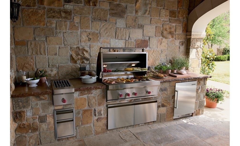 The Wolf 42" Outdoor Gas Grill (OG42) shown offering state-of-the-art kitchen amenities in a warm and rustic outdoor kitchen design.