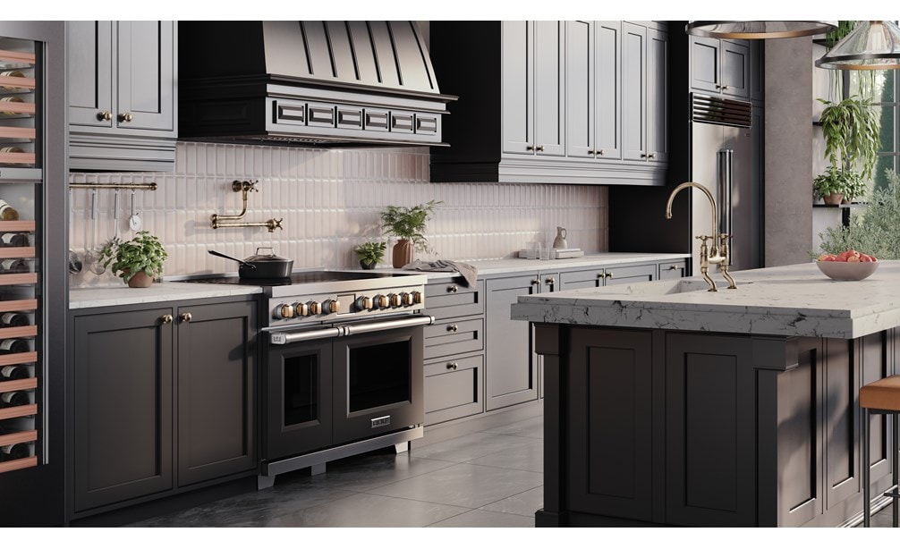 Wolf Professional Induction Range with black accent oven door and brass knobs shown in a modern bohemian kitchen design featuring custom grey kitchen cabinets enclosing a Wolf Pro Hood Liner.
