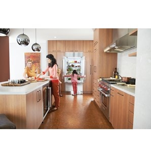 The Wolf 36" Low Profile Wall Hood (PW362210) shown illuminating cooking surface in large family friendly galley style kitchen