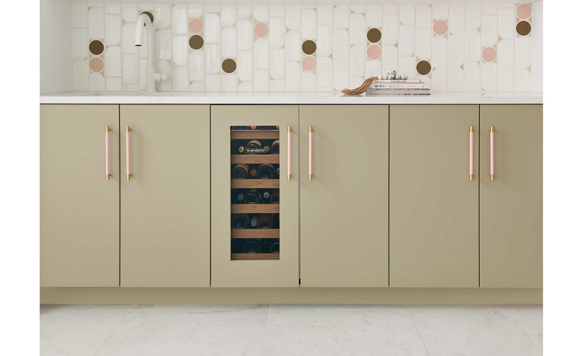 Frontal view of closed Sub-Zero 15" Designer Undercounter Beverage Center with Solid Door - Panel Ready (DEU1550B) shown in a row of tan custom cabinets