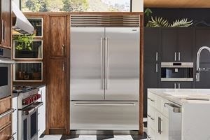 Sub-Zero Classic Series Refrigerator built into stained wood custom cabinetry in sunlit and earthy kitchen