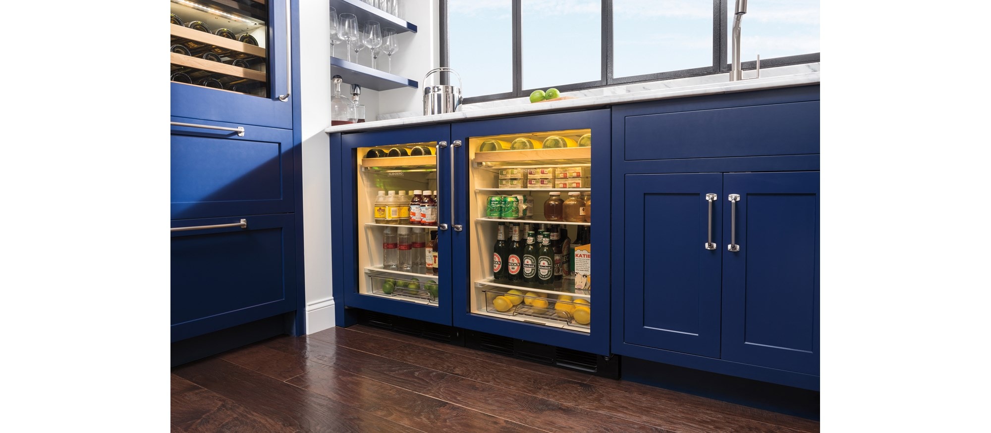 Paired Sub-Zero Undercounter Beverage Center featuring glass doors, custom panels and chrome handles