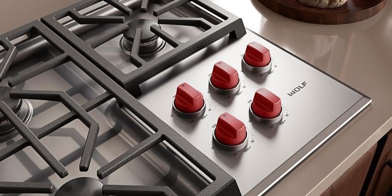Wolf M Series 36 inch Gas Cooktop (Professional) shown with premium grade stainless steel and iconic red knobs.