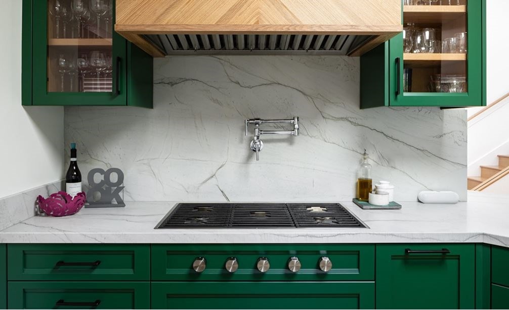 Wolf 36-inch contemporary gas cooktop featured in small space stylish kitchen with green cabinets and marble backsplash.