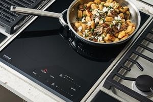 Wolf 15" transitional induction cooktop module (CI152TFS) paired with a 15" transitional grill module (GM15TFS) and 15" transitional gas cooktop module (CE152TFS)