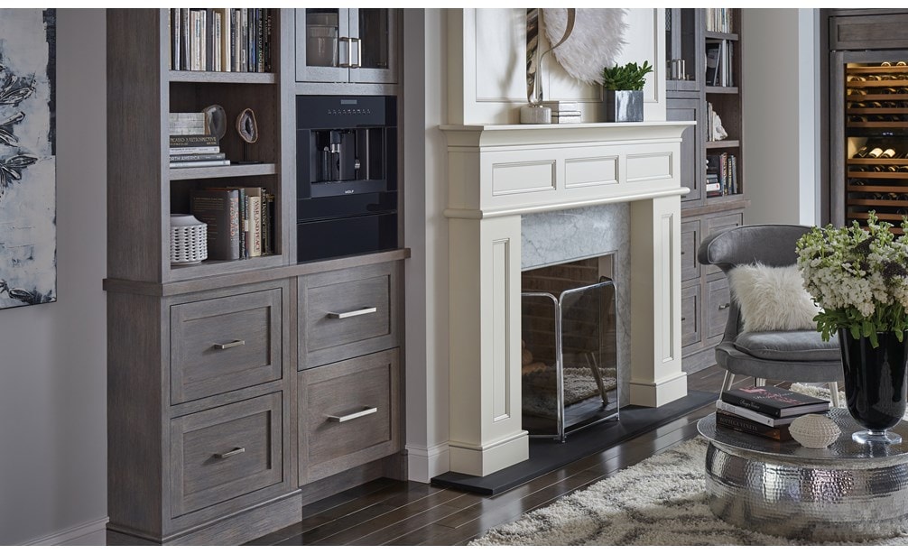 The Wolf 24" Coffee System Black Glass (EC24/B) shown set seamlessly in bookshelf featuring warm wood tones and modern handles