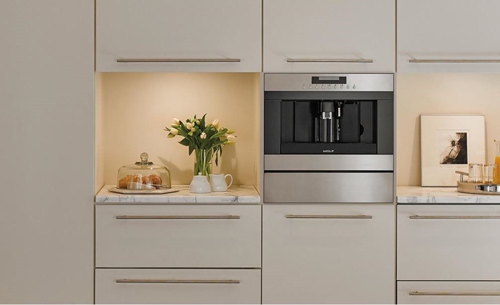 The Wolf 24&quot; Coffee System Stainless Steel (EC24/S) featured in open bright room set flush in smooth white seamless cabinets