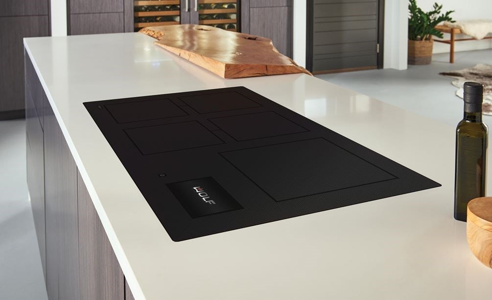Wolf 36 Contemporary Induction Cooktop (CI36560C/B) featured in a modern kitchen design, blending seamlessly into smooth white countertops with warm wood tone cabinets.