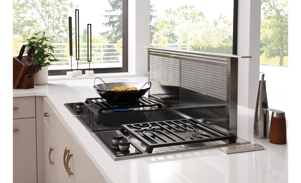 The Wolf 15" Transitional Induction Cooktop (CI152TF/S) shown set flush in artistic black and white speckled granite countertop