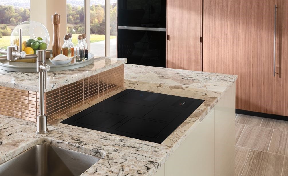 Wolf 30" Contemporary Induction Cooktop shown flush mounted in gray and white marble kitchen countertop.