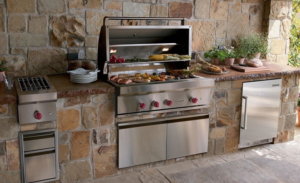 The Wolf 42" Outdoor Gas Grill (OG42) shown offering state-of-the-art kitchen amenities in a warm and rustic outdoor kitchen design.