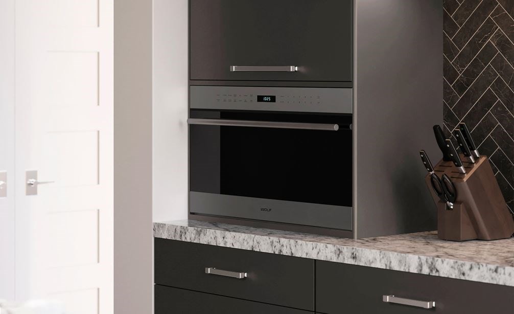 Wolf 30&quot; E Series Transitional Drop-Down Door Microwave Oven (MDD30TE/S/TH) set expertly in smooth cabinetry against gray backsplash
