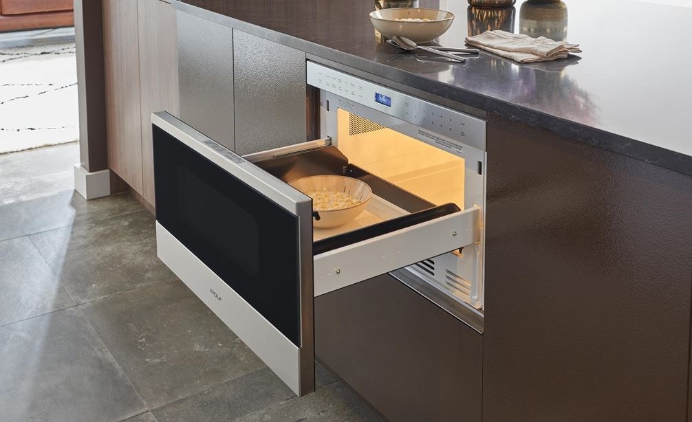 The Wolf 24&quot; Transitional Drawer Microwave (MD24TE/S) shown here adding polish set flush in a wall of ultra-modern smooth cabinetry