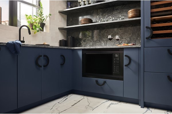 Wolf Standard Swing Microwave flushed with the cabinetry of a luxury, blue-colored kitchen.
