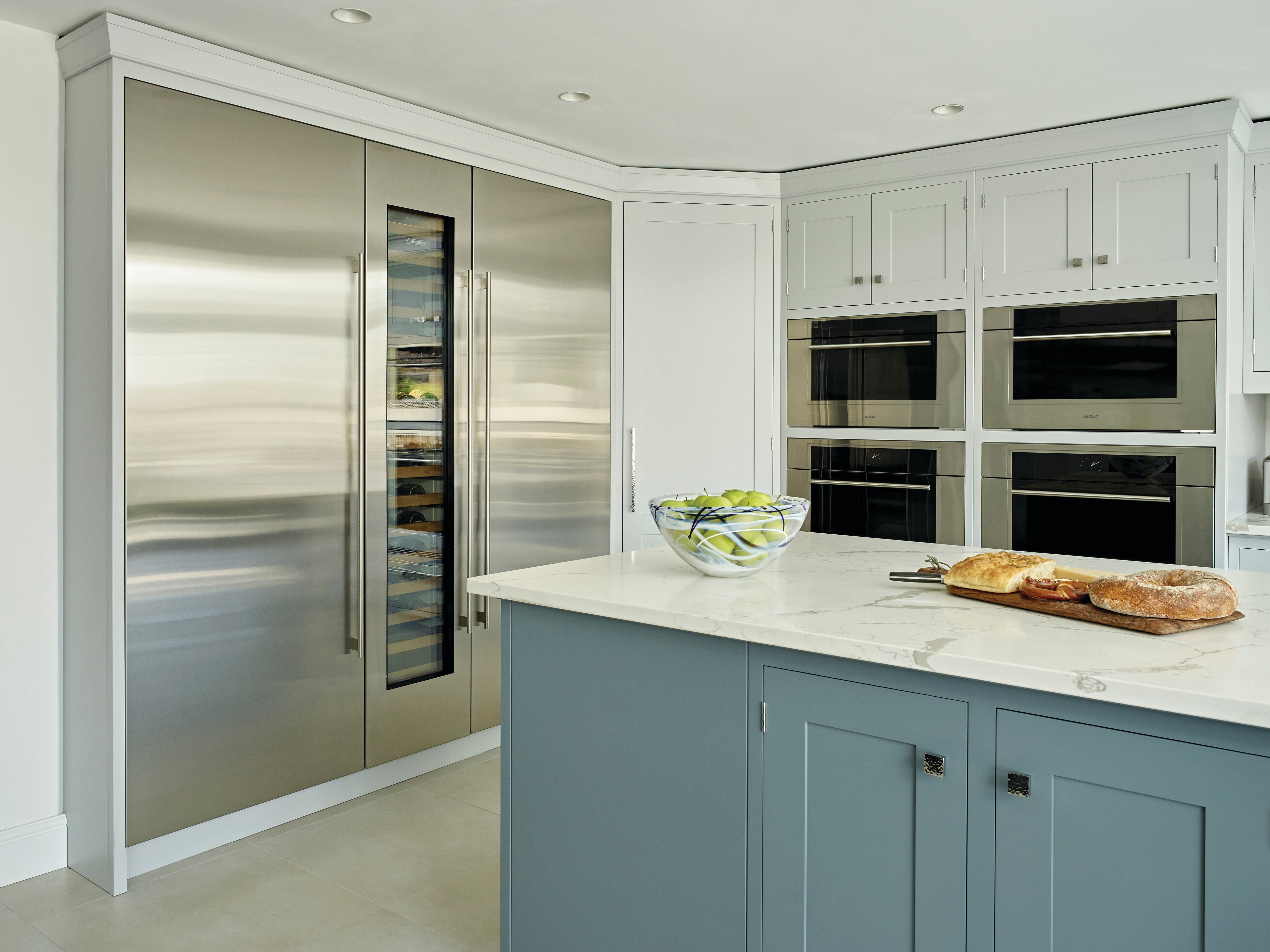 The Wolf 30" M Series Transitional Speed Oven - SPO3050TM/S/T next to a Wolf Convection Steam Oven in a blue kitchen