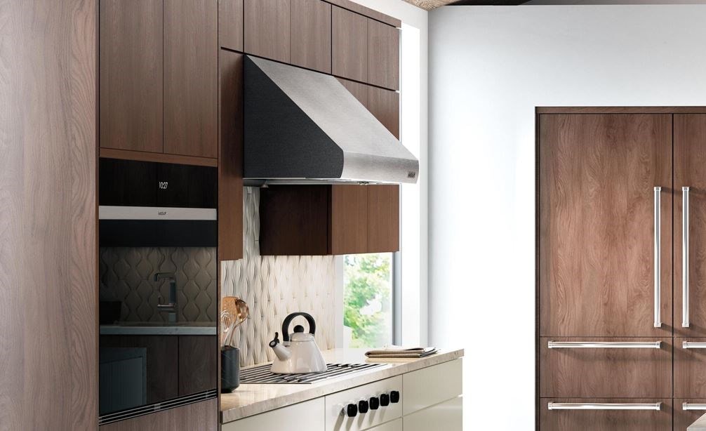 The Wolf 36&quot; Pro Wall Hood - 27&quot; Depth (PW362718) shown in a large luxury kitchen concept featuring smooth wood panel cabinetry