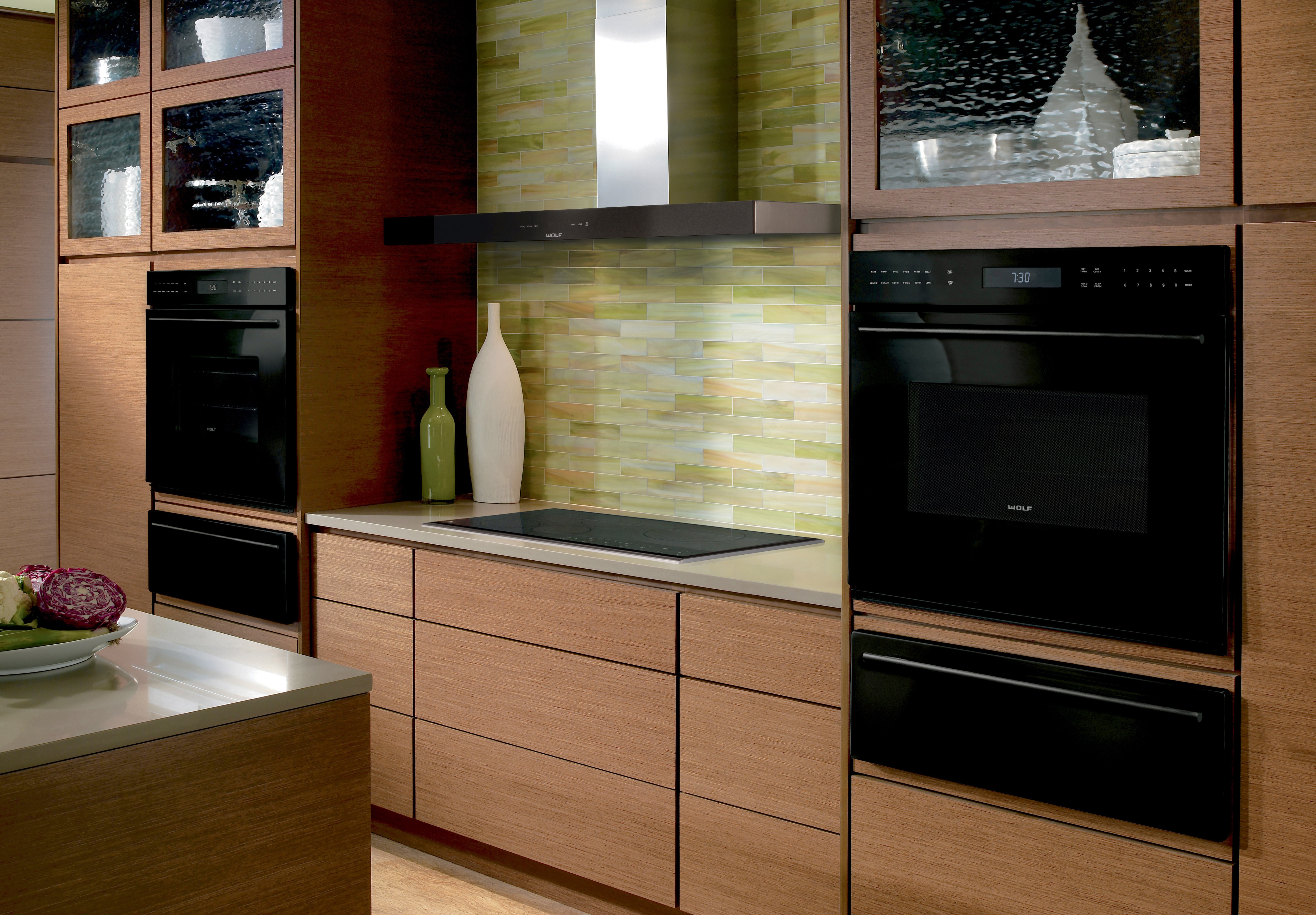 The Wolf 45" Cooktop Wall Hood - Black (VW45B) shown with a variety of Wolf cooking appliances in warm contemporary kitchen