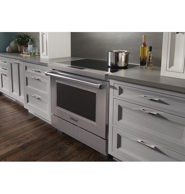 Wolf 36" Professional Induction Range (IR36550/S/P) featured in gray cabinetry with a stainless steel pot on it ceramic black glass surface.
