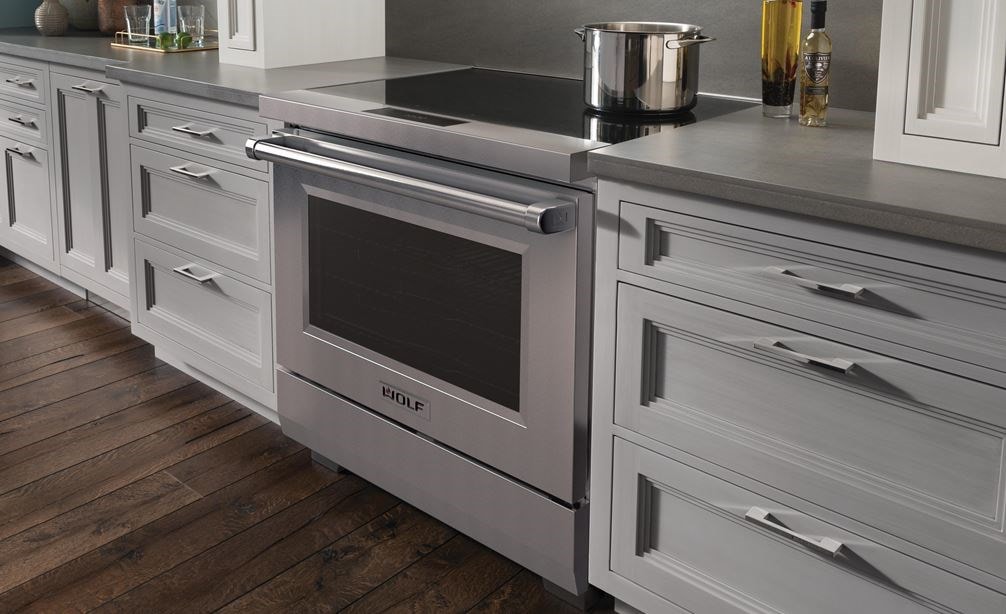 Wolf 36&#34; Professional Induction Range (IR36550/S/P) featured in gray cabinetry with a stainless steel pot on it ceramic black glass surface.